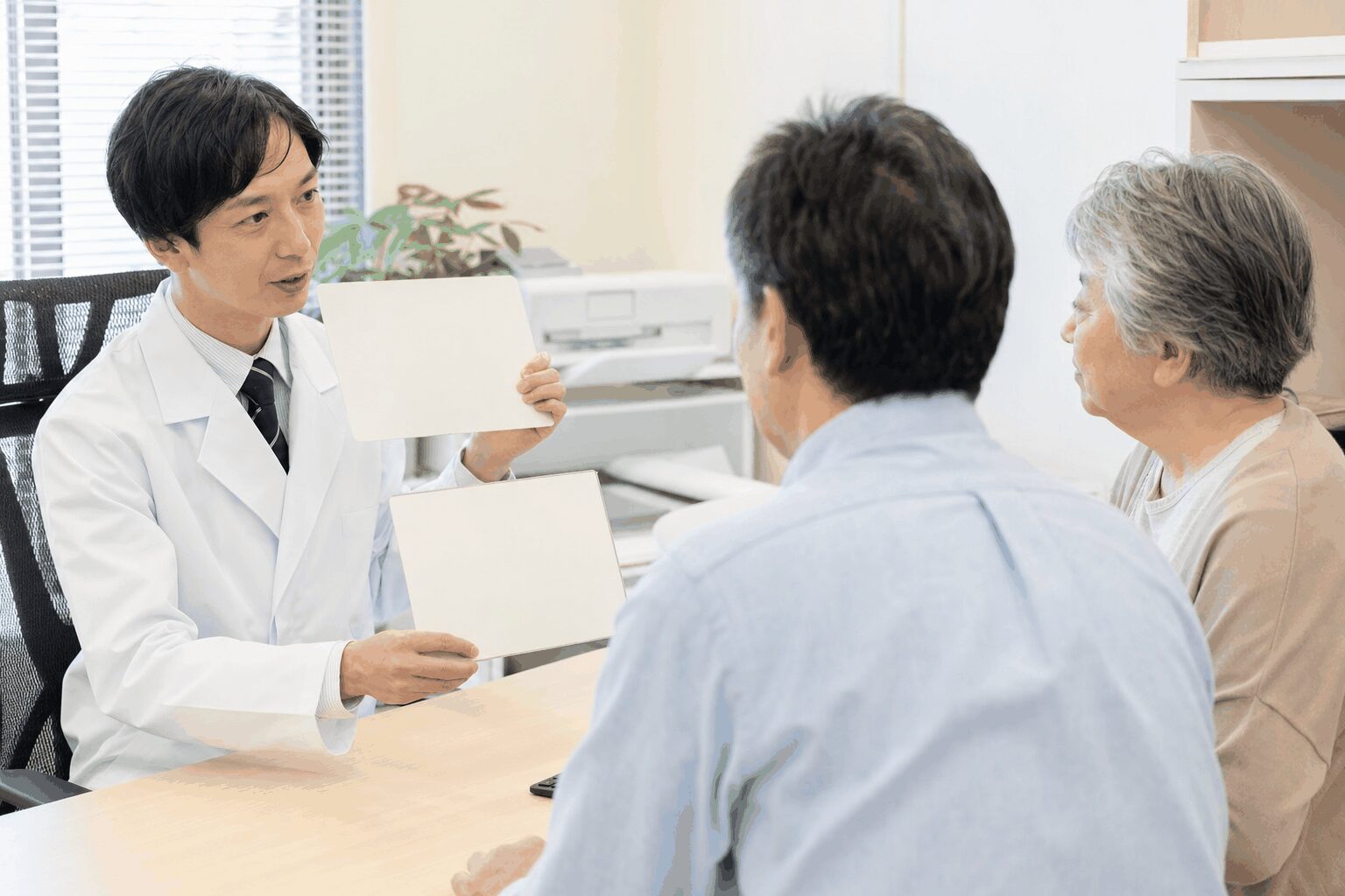 医師が中高年の患者に大腸がん検診と精密検査を説明する様子